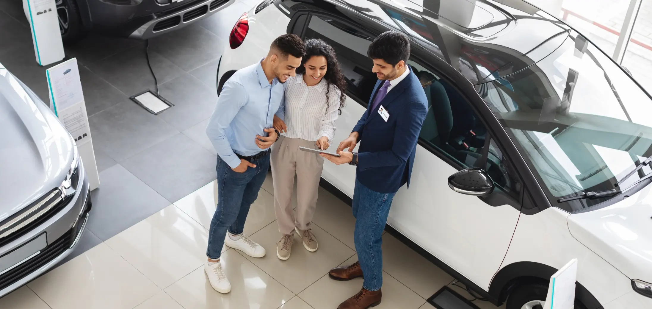 A car salesman presents a vehicle to a couple of customers
